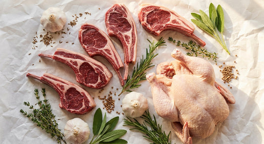 A flat-lay of fresh premium halal meat cuts including lamb chops and whole chicken arranged on white butcher paper with fresh herbs and warm spices, lit by soft natural light.